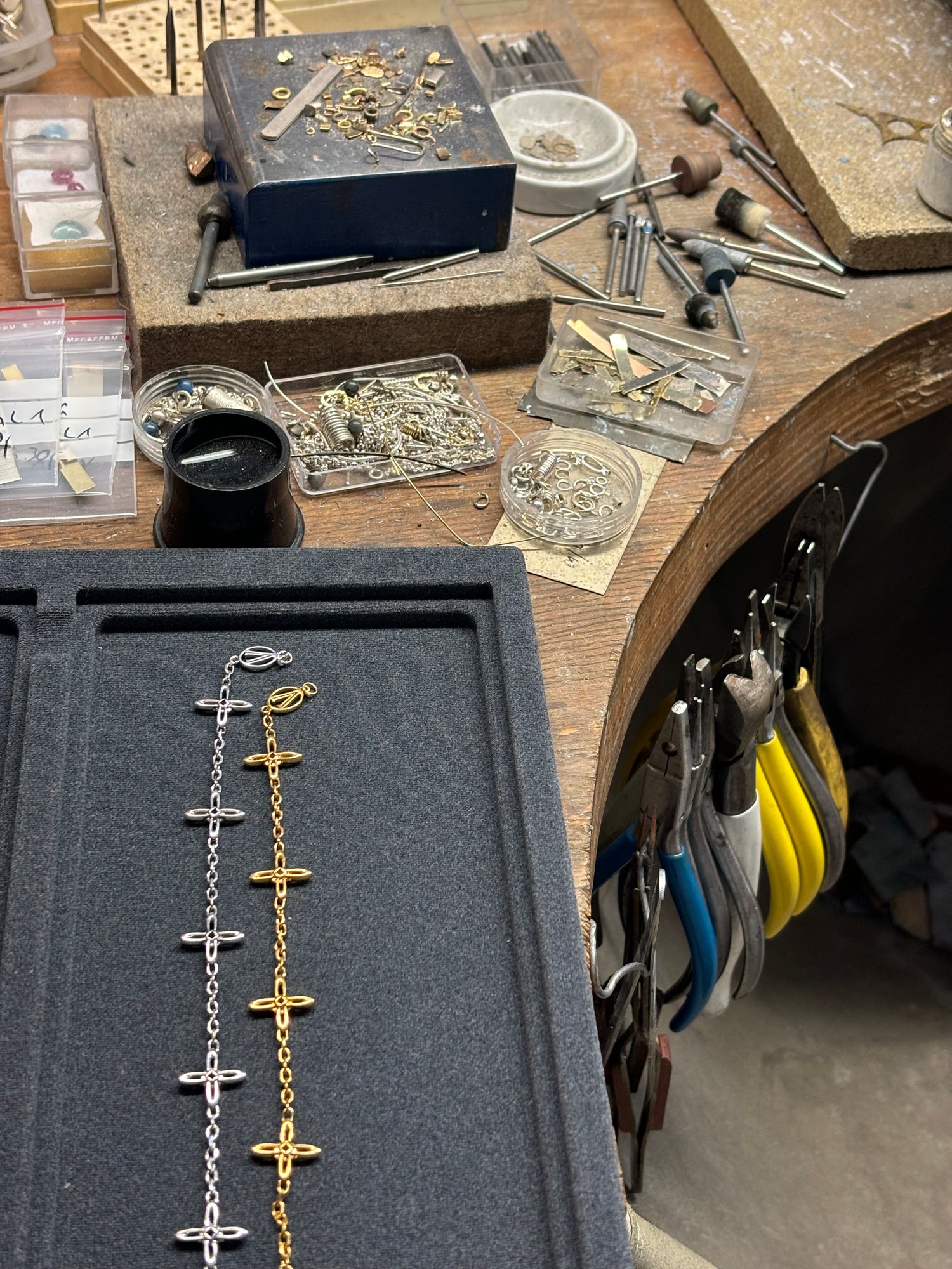 Italienische Schmuckproduktion – handgefertigte Armbänder auf Werkbank mit Werkzeugen und Materialien