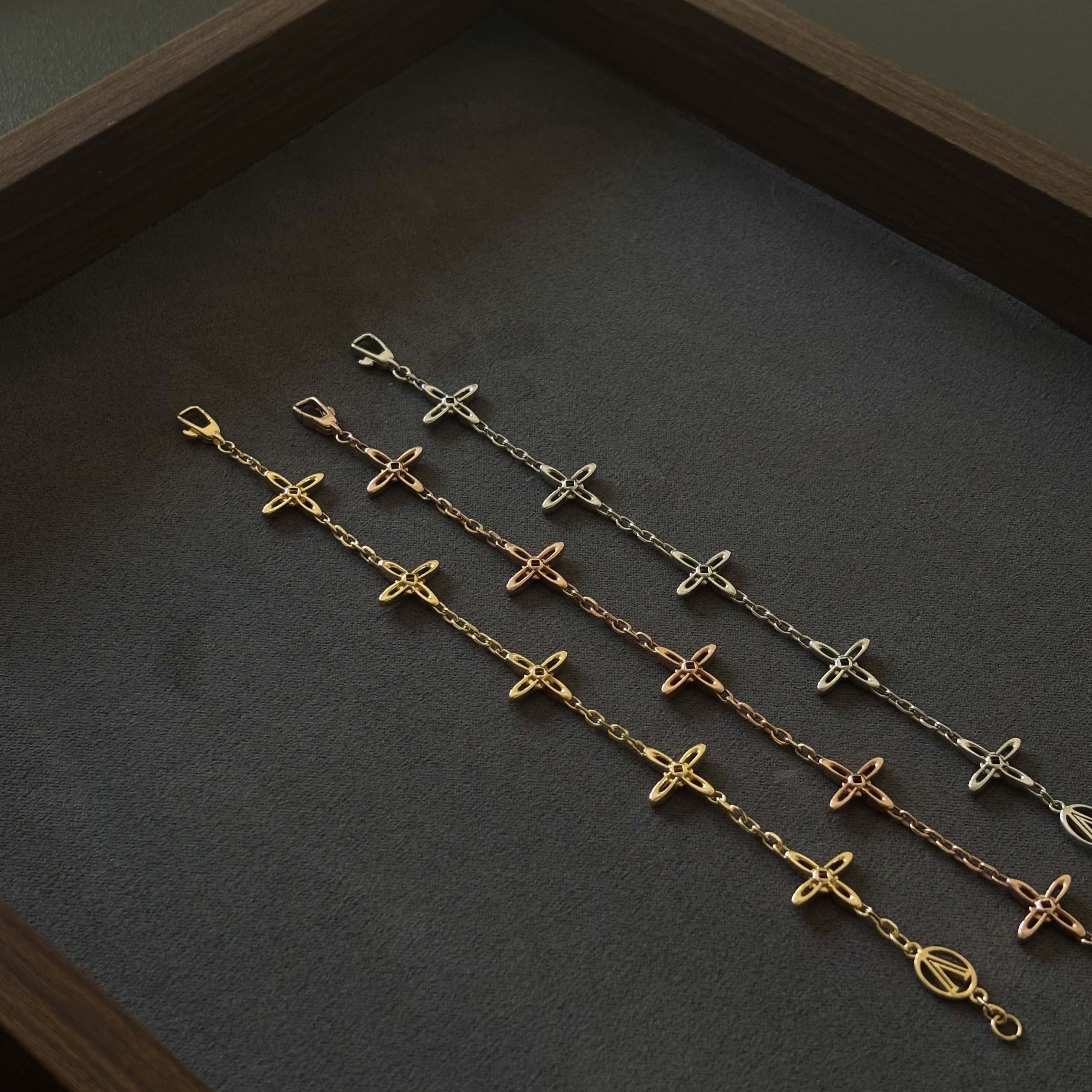 Drei Celestial Armbänder in Gold, Roségold und Silber von Ovis & Co auf dunklem Untergrund, filigranes Design mit Kreuzanhängern.