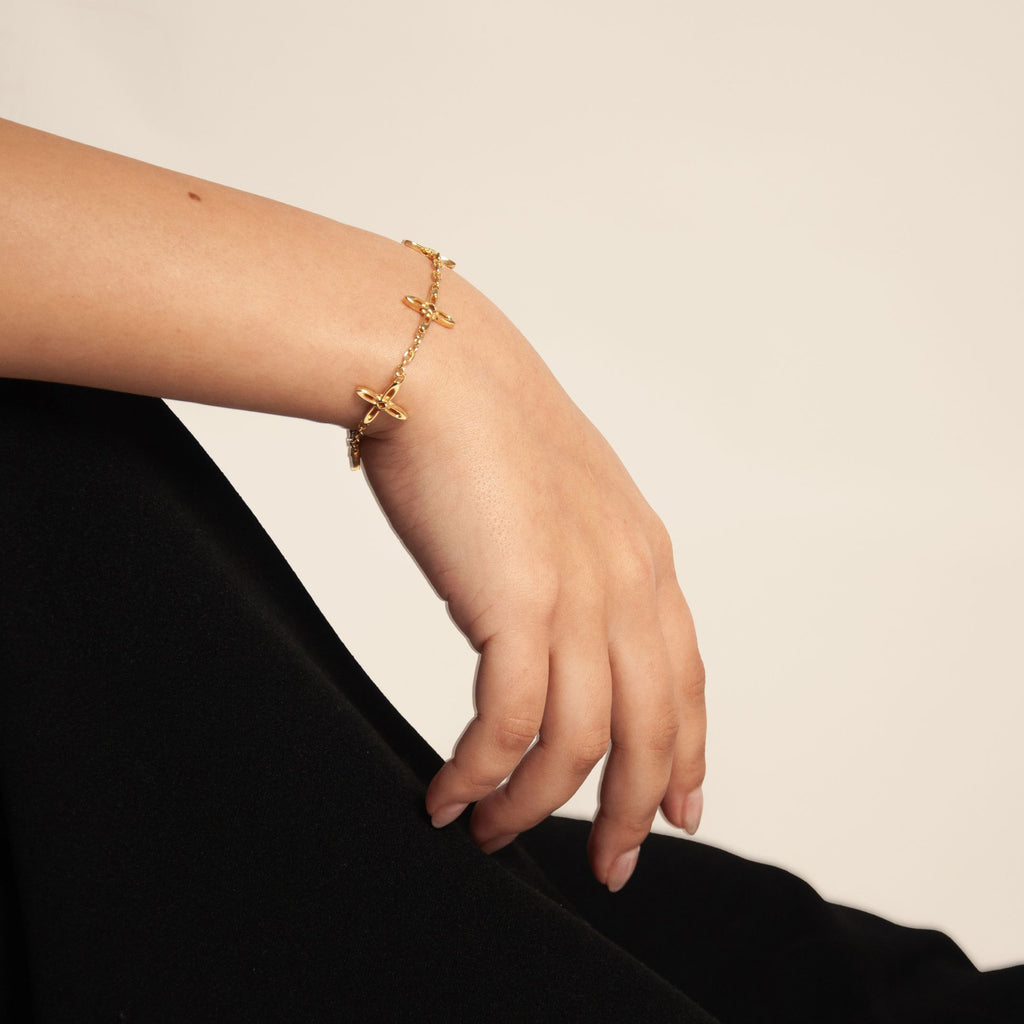 Ovis & Co. Celestial Armband Gold – minimalistisches Edelstahlarmband mit 5 filigranen Anhängern, getragen von Frau zu schwarzem Satin-Rock, langlebige Veredelung, designed in Frankfurt