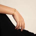 Ovis & Co. Celestial Armband Gold – minimalistisches Edelstahlarmband mit 5 filigranen Anhängern, getragen von Frau zu schwarzem Satin-Rock, langlebige Veredelung, designed in Frankfurt