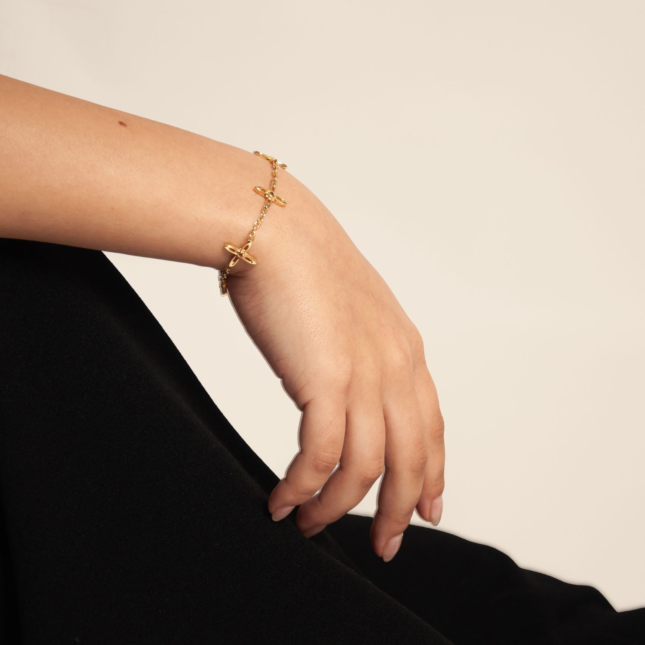 Ovis & Co. Celestial Armband Gold – minimalistisches Edelstahlarmband mit 5 filigranen Anhängern, getragen von Frau zu schwarzem Satin-Rock, langlebige Veredelung, designed in Frankfurt
