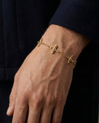 Ovis & Co. Celestial Armband Gold – Edelstahlarmband mit 5 filigranen Anhängern, getragen von Mann zu dunkelblauem Wollmantel, langlebige Veredelung, designed in Frankfurt