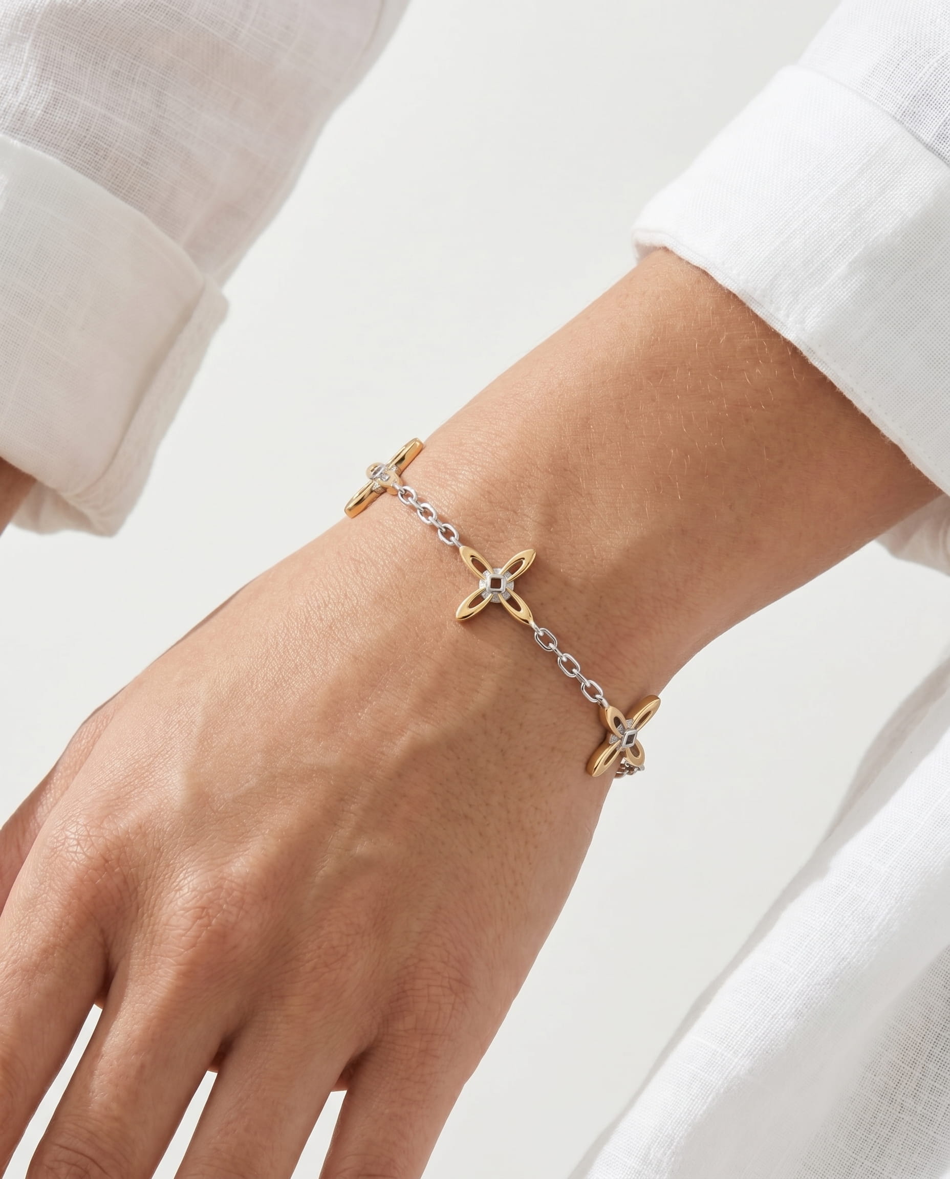 Ovis & Co. Celestial Armband Two-Tone – Edelstahlarmband mit 5 filigranen Anhängern in Gold und Silber, getragen zu weißem Leinenhemd, designed in Frankfurt