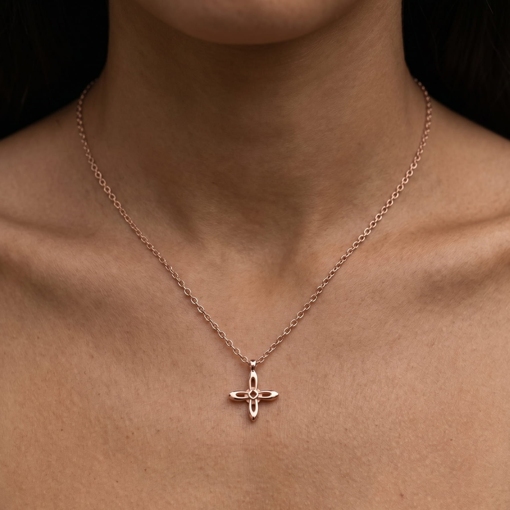 Ovis & Co. Celestial Kette Roségold – minimalistische Edelstahlkette mit filigranem Kreuz-Anhänger, getragen von Frau auf nacktem Décolleté, langlebige Veredelung, designed in Frankfurt