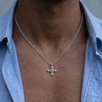 Ovis & Co. Celestial Kette Silber – minimalistische Edelstahlkette mit filigranem Kreuz-Anhänger, getragen von Mann mit offenem hellblauen Hemd, designed in Frankfurt