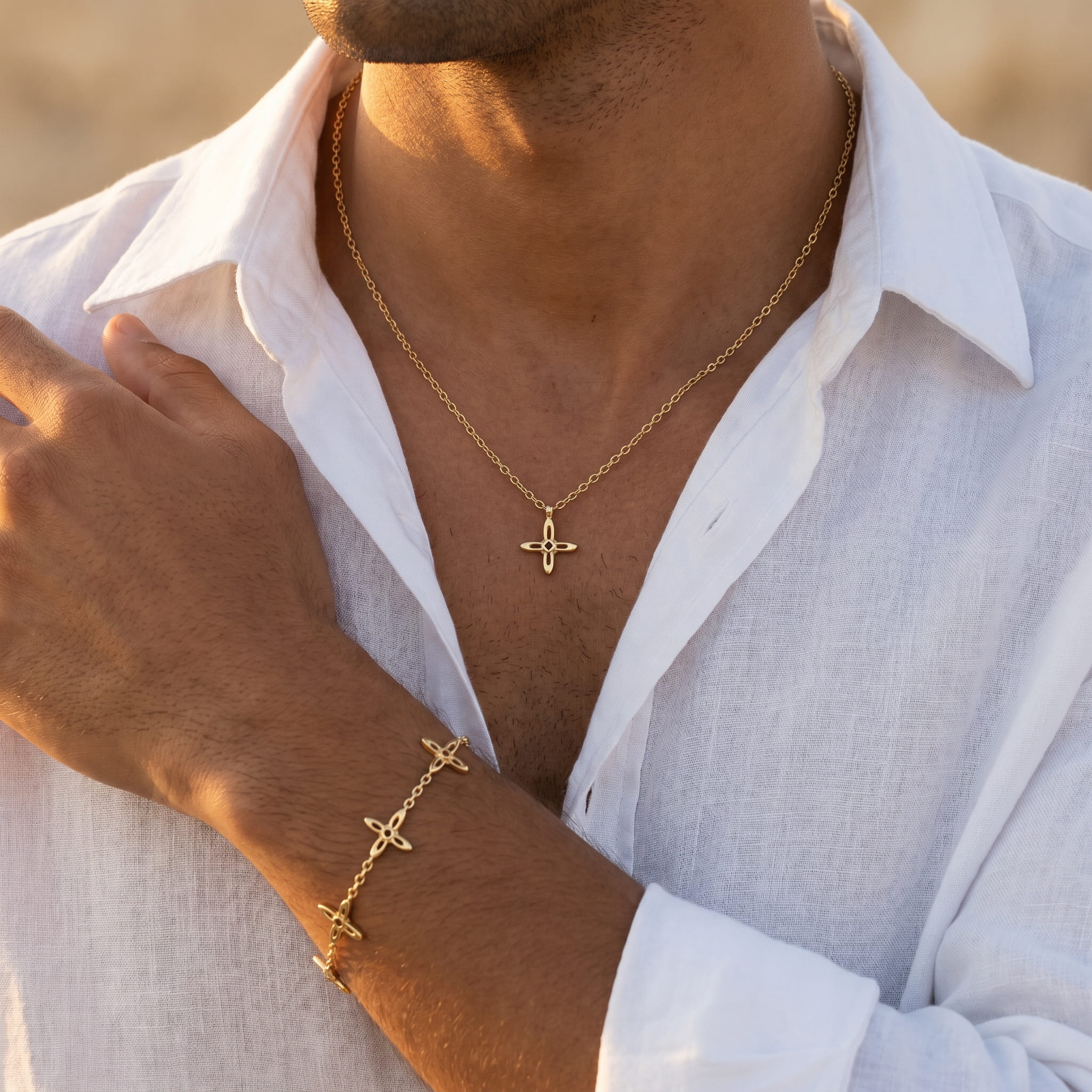Ovis & Co. Celestial Set Gold – Edelstahlkette mit Anhänger und Armband mit 5 filigranen Anhängern, getragen von Mann mit offenem weißen Leinenhemd im Gegenlicht, langlebige Veredelung, designed in Frankfurt