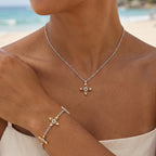 Ovis & Co. Celestial Set Two-Tone – Edelstahlkette mit goldenem Anhänger und Armband mit 5 filigranen Anhängern in Silber und Gold, getragen von Frau am Strand zu beigem Top, designed in Frankfurt