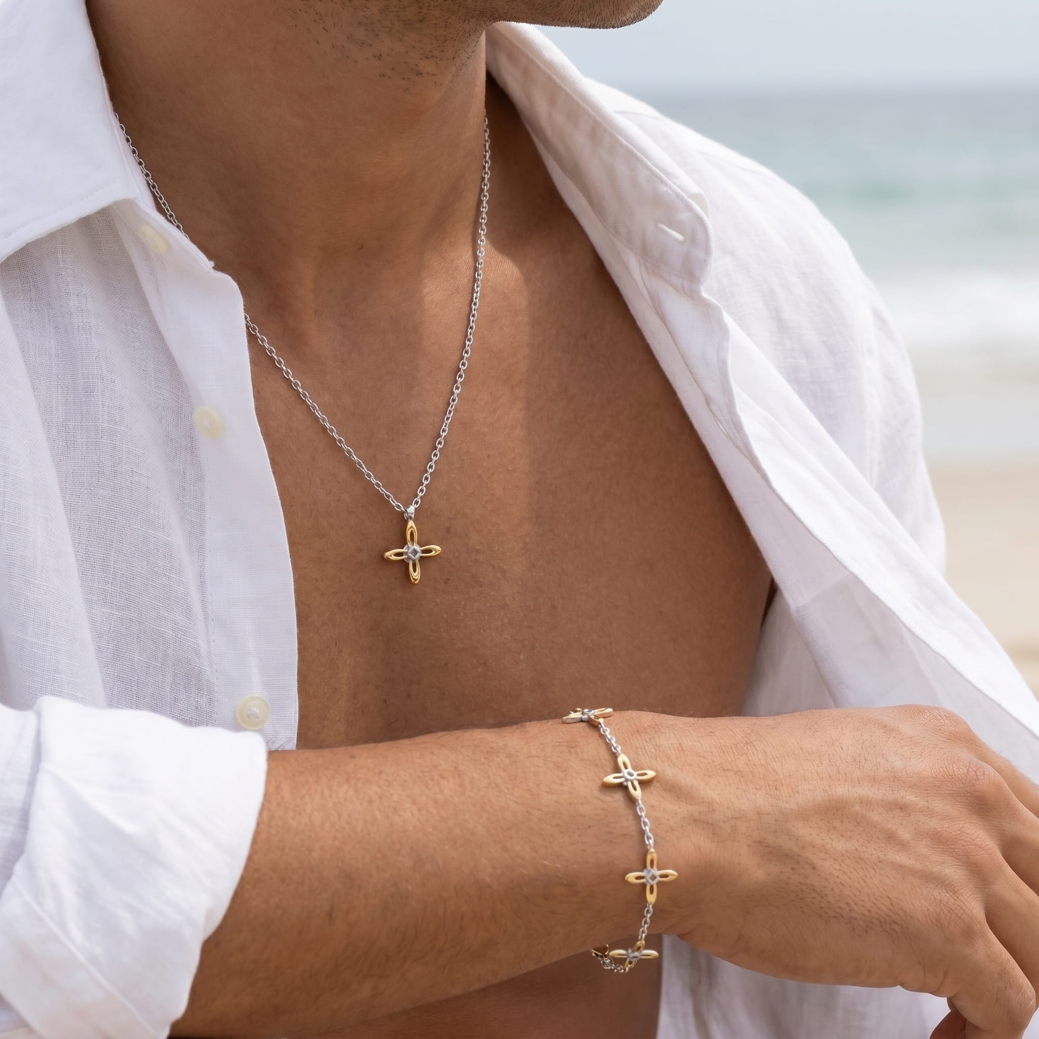 Ovis & Co. Celestial Set Two-Tone – Edelstahlkette mit goldenem Anhänger und Armband mit 5 filigranen Anhängern in Silber und Gold, getragen von Mann am Strand zu weißem Leinenhemd, designed in Frankfurt